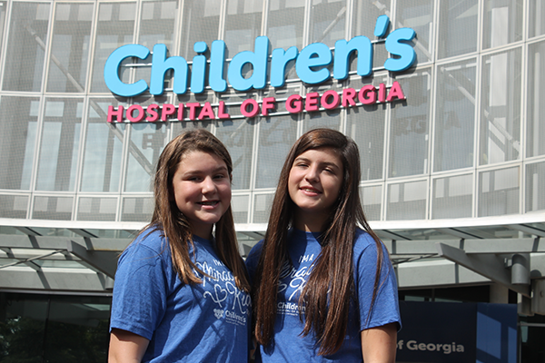 Two teenage girls smile in front of Children's Hospital of Georgia.