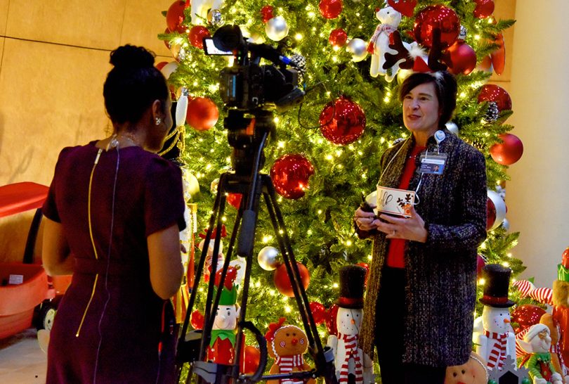 reporter interviewing woman in front of Christmas tree